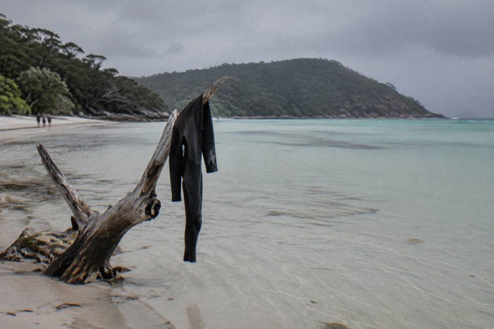 Clear shallow water over pale sand at Whitehaven Beach with a wooded headland in the distance