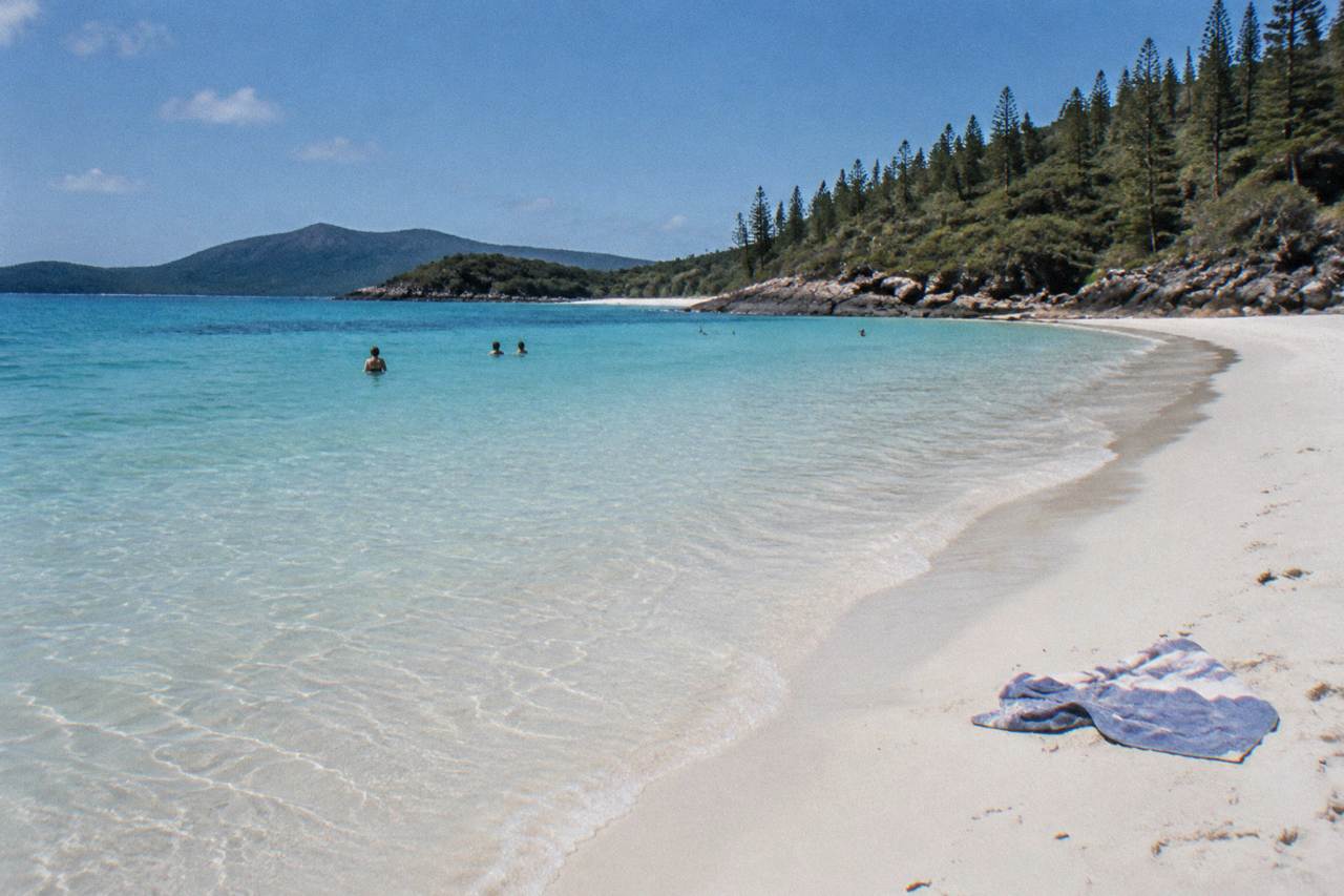 Whitehaven Beach curving between green headlands with pale silica sand and clear shallow water