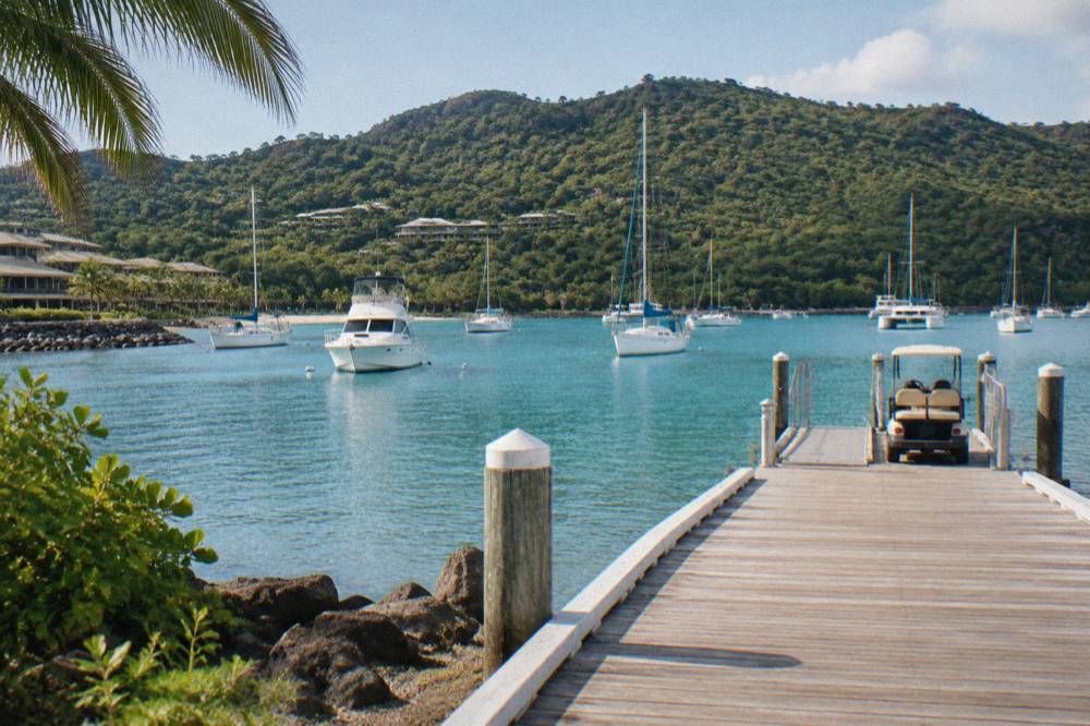 Anchored boats in a calm bay with dense green hills behind them