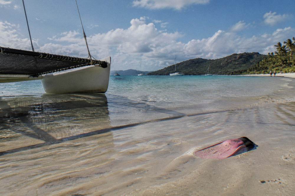 White sand beach meeting clear shallow water under a wide sky