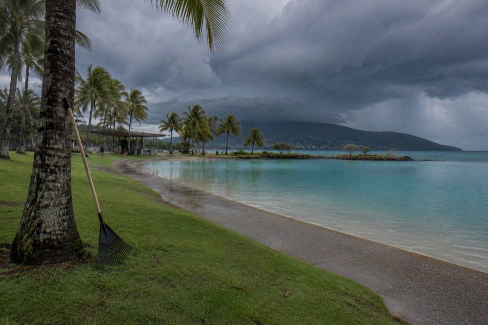 A wide tropical swimming lagoon edged by palm trees and lawns beside the sea