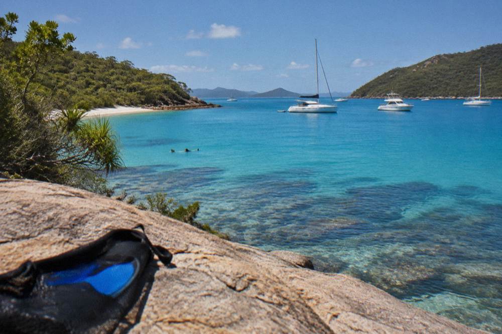 Anchored boats in a calm bay between green Whitsunday islands at midday
