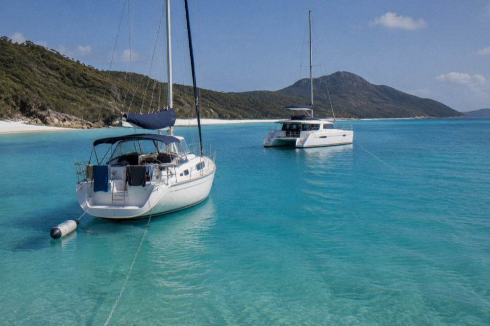 Anchored charter boats in calm blue water near a white sand beach