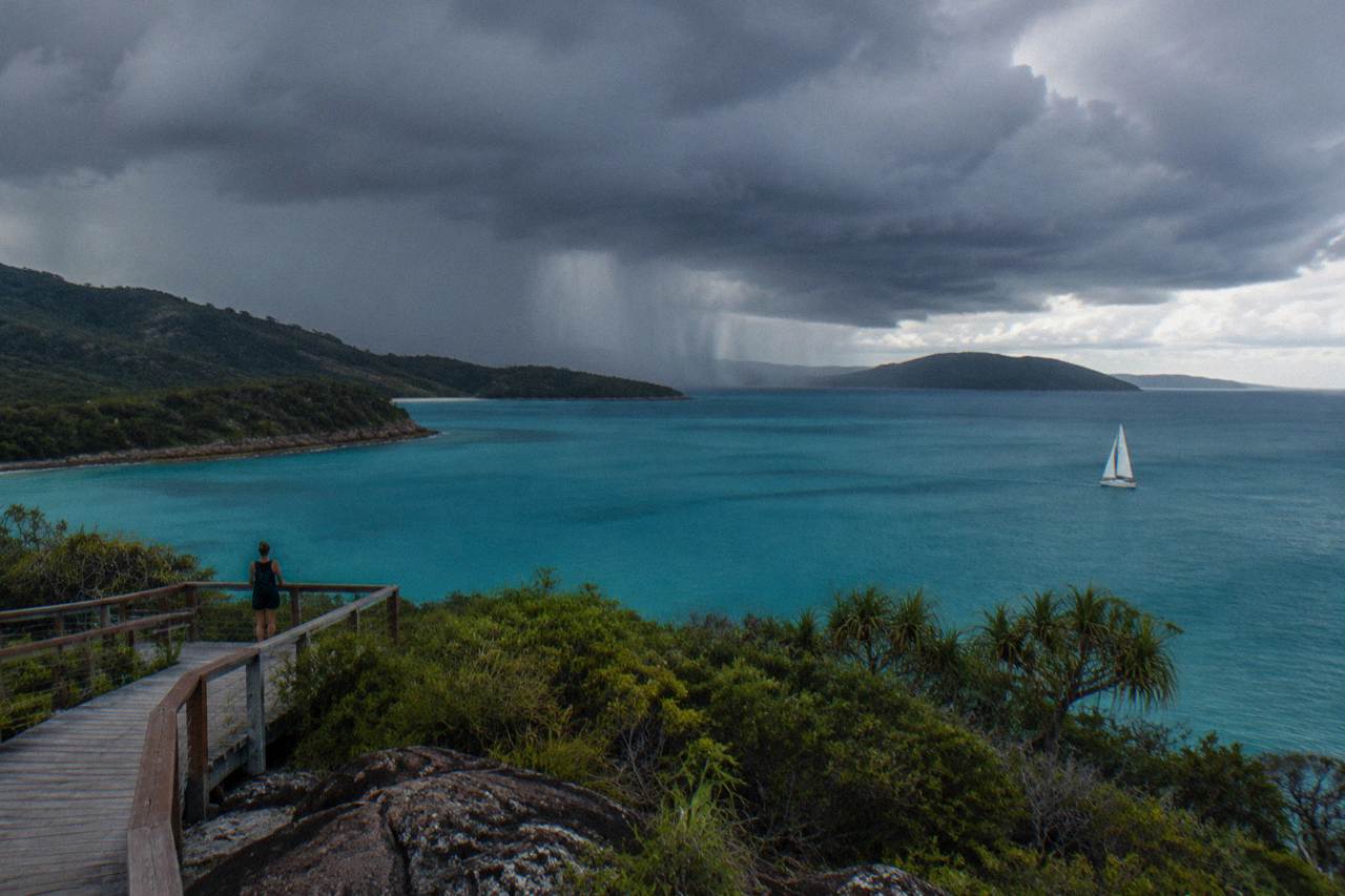 Dark storm clouds building over calm turquoise island water
