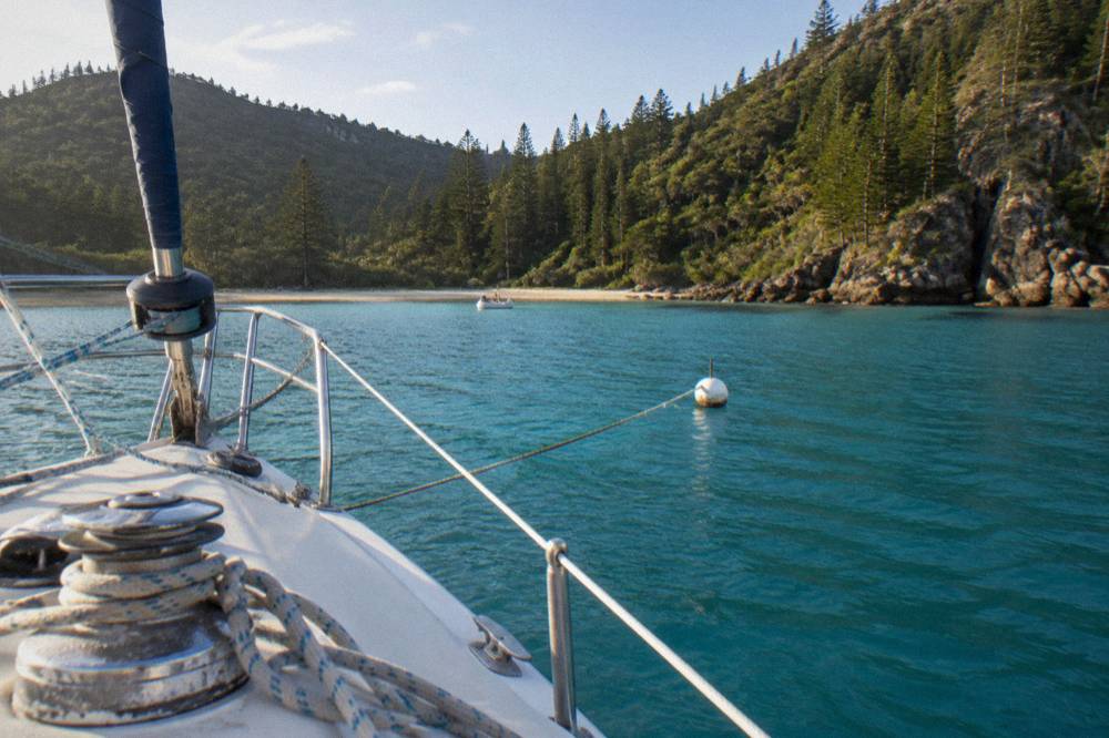 Turquoise bay between wooded islands with a moored sailing boat