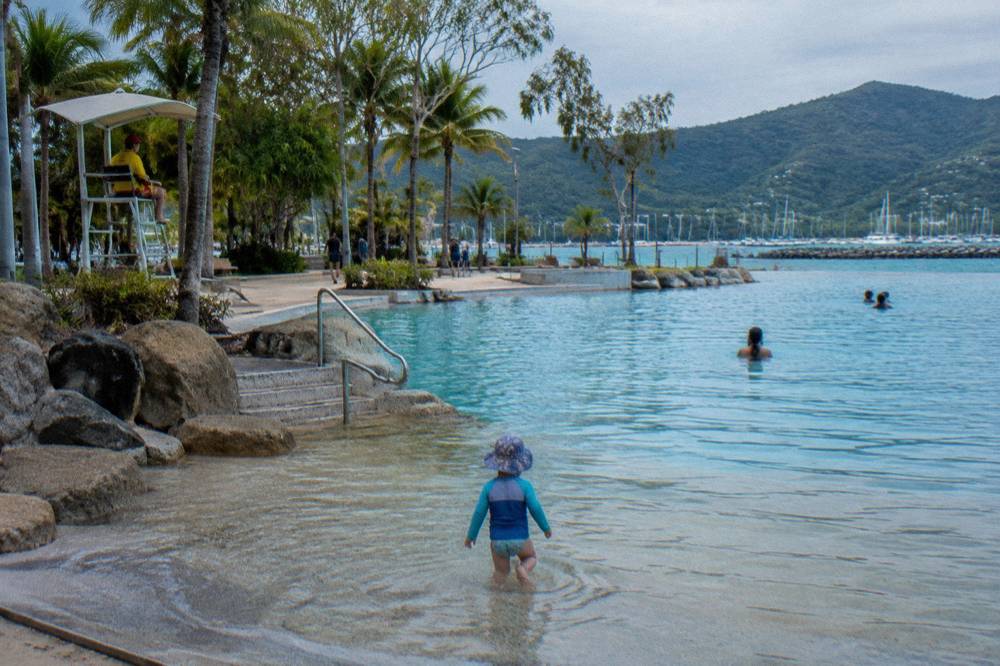 A patrolled swimming lagoon with marked lanes and shaded lawn areas along the edge