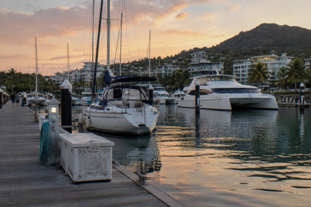 A marina with moored sailing boats and cruise vessels at a tropical resort town