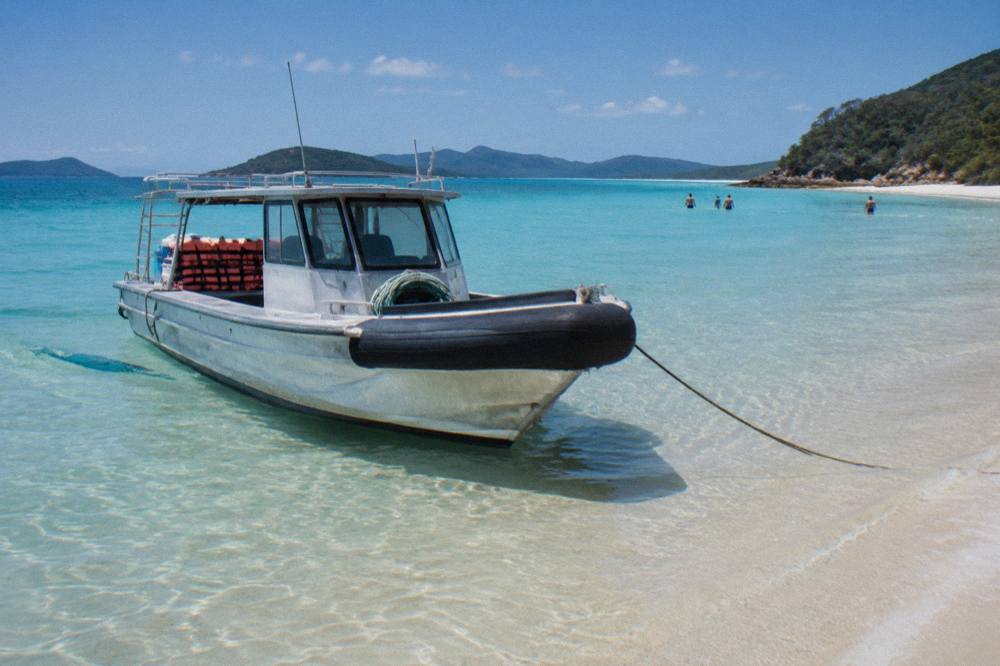 A fast tour boat moored close to white sand at Whitehaven Beach