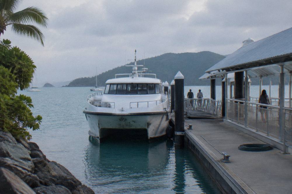 A ferry berthed at a modern marina terminal with islands on the horizon