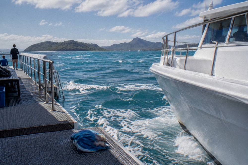 A floating pontoon moored over clear reef water with a moored vessel alongside