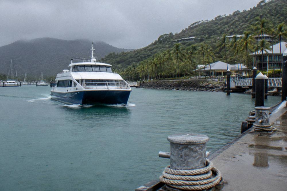 A passenger ferry crossing open water toward a resort island jetty