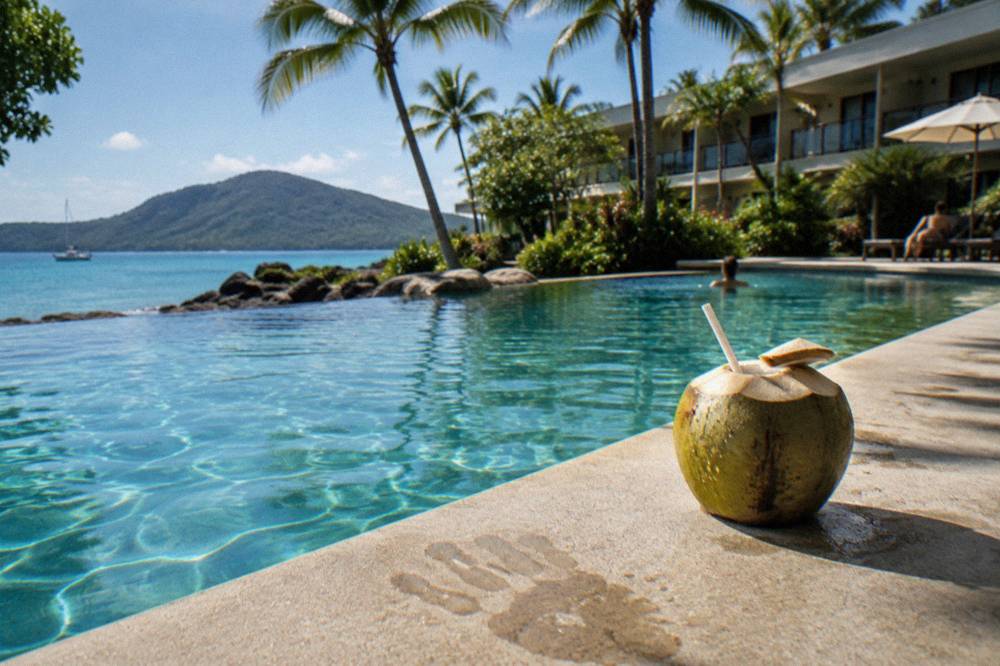 A lagoon-style swimming pool fringed by palm trees beside a resort building