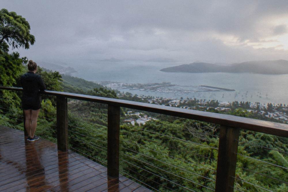 Wooden lookout platform above dense green rainforest with islands visible on the horizon