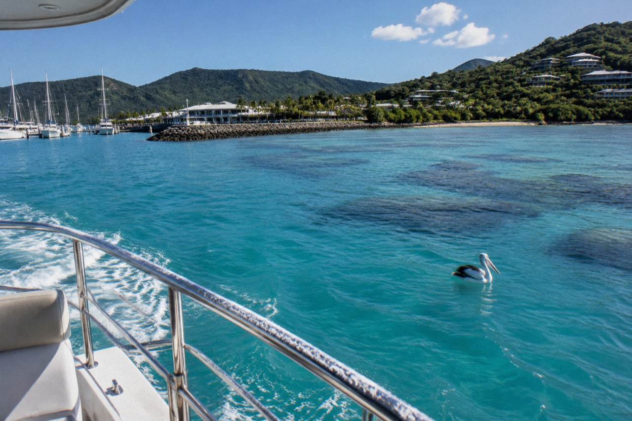 Turquoise reef water and coral formations seen from a boat deck near an island coastline