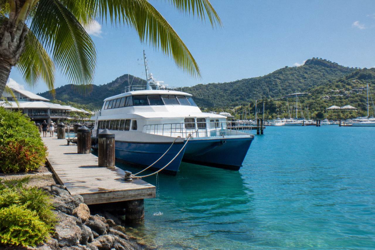 Ferry moored at a tropical island marina with palm trees and blue water