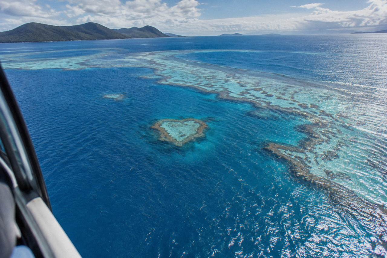 A heart shaped coral reef visible through clear blue water among the Whitsunday islands