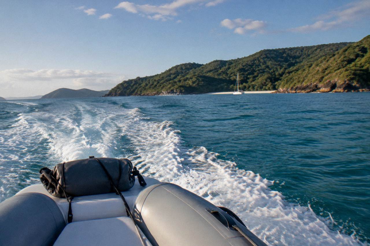 Inflatable speedboat cutting across open water toward green Whitsunday islands