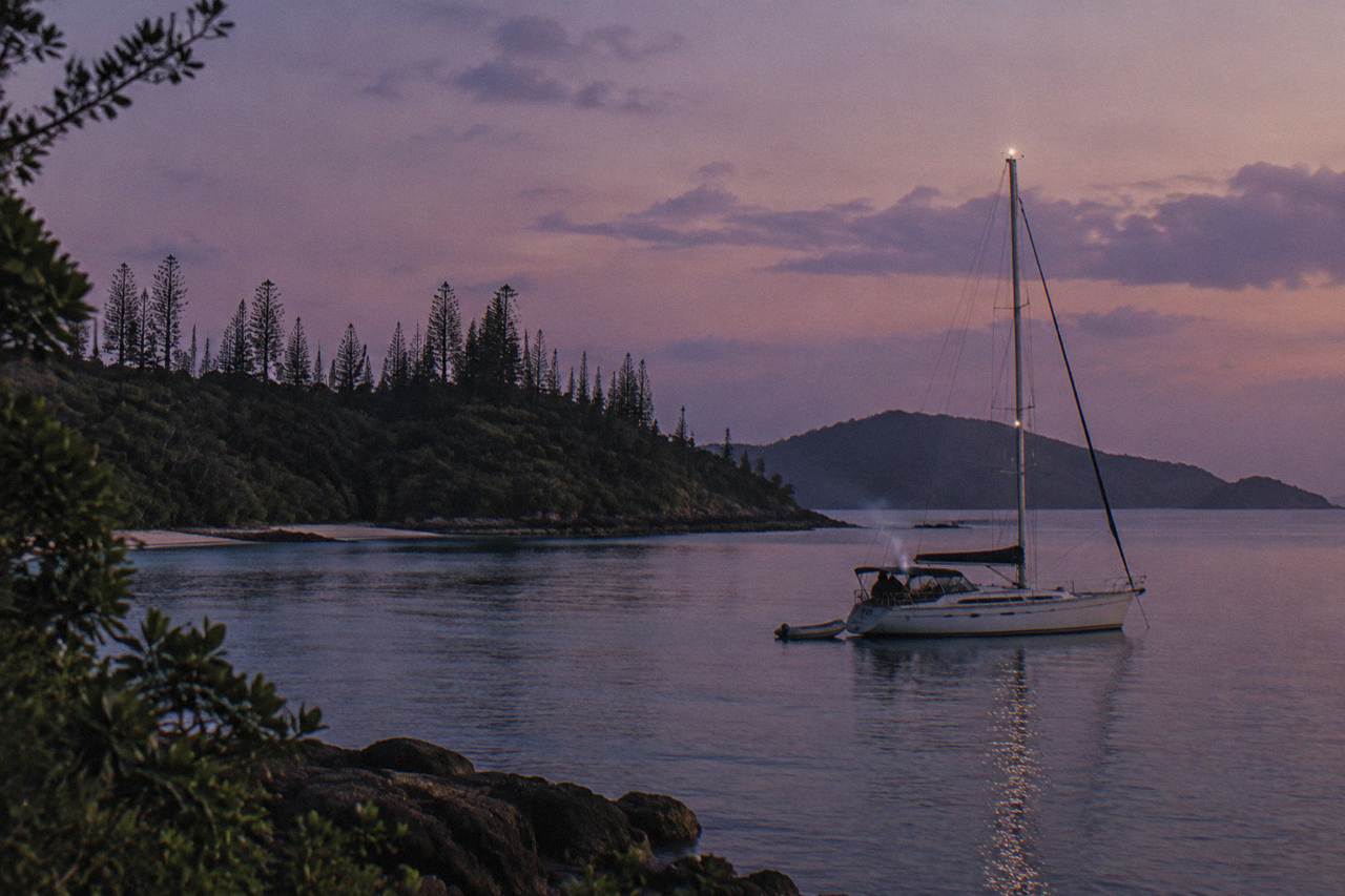 A sailing yacht anchored in a calm Whitsunday island bay at dusk