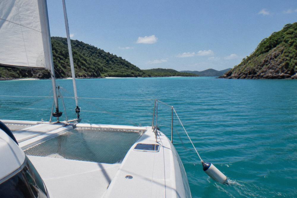 White catamaran cruising past green islands on calm turquoise water