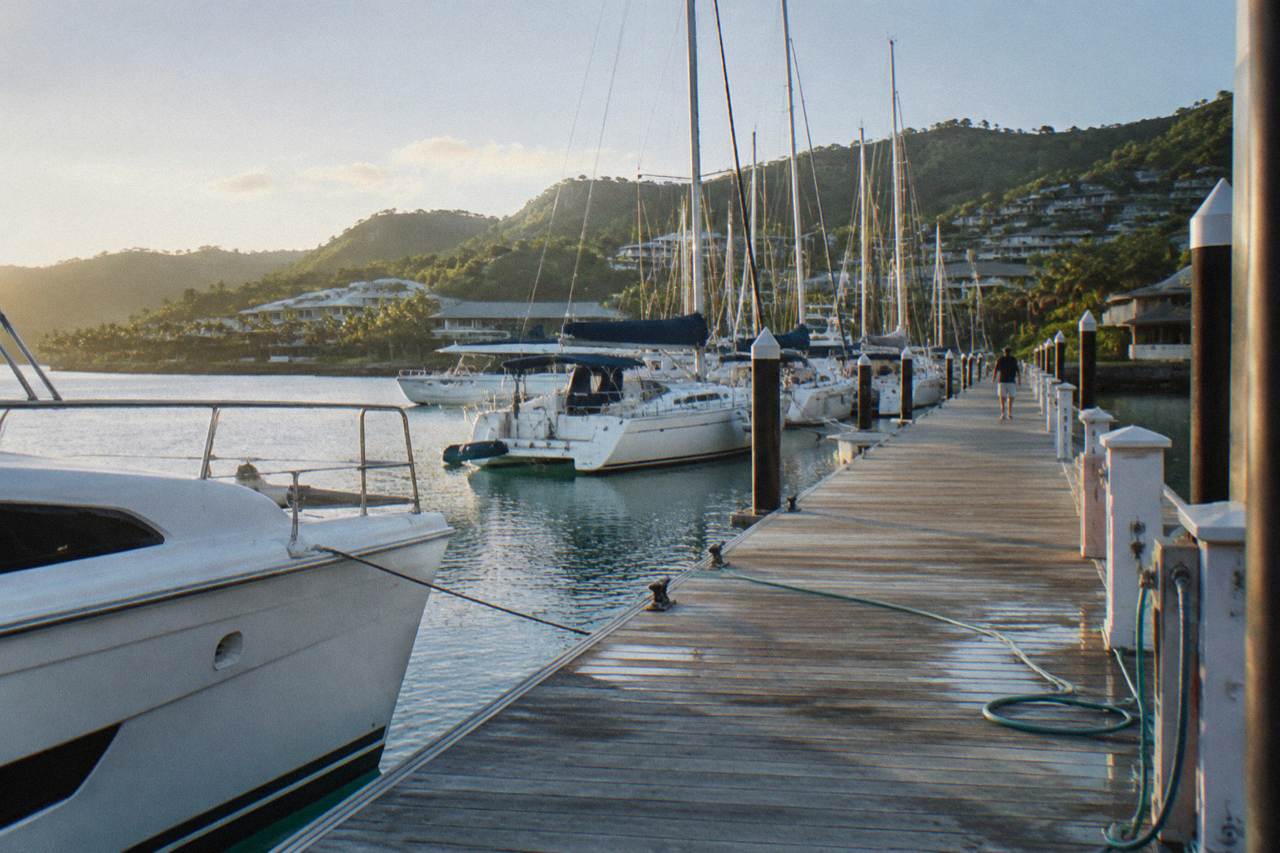 Hamilton Island marina with yachts moored along the jetty and green hills rising behind