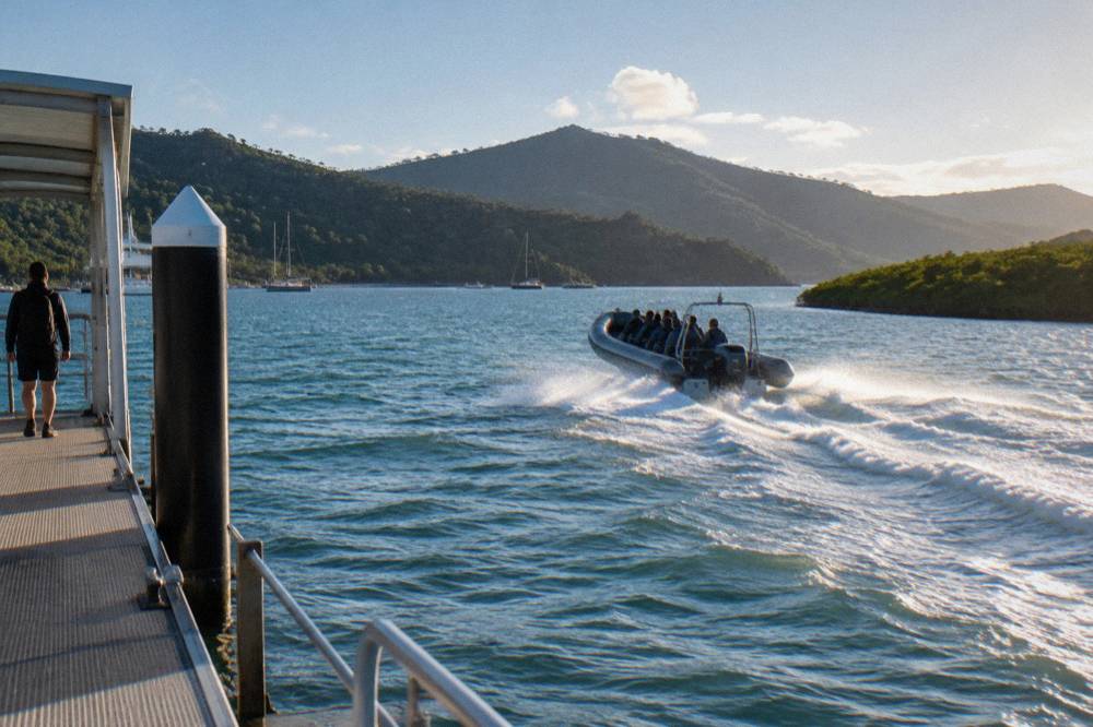 An inflatable ocean rafting boat speeding across open water between green Whitsunday islands