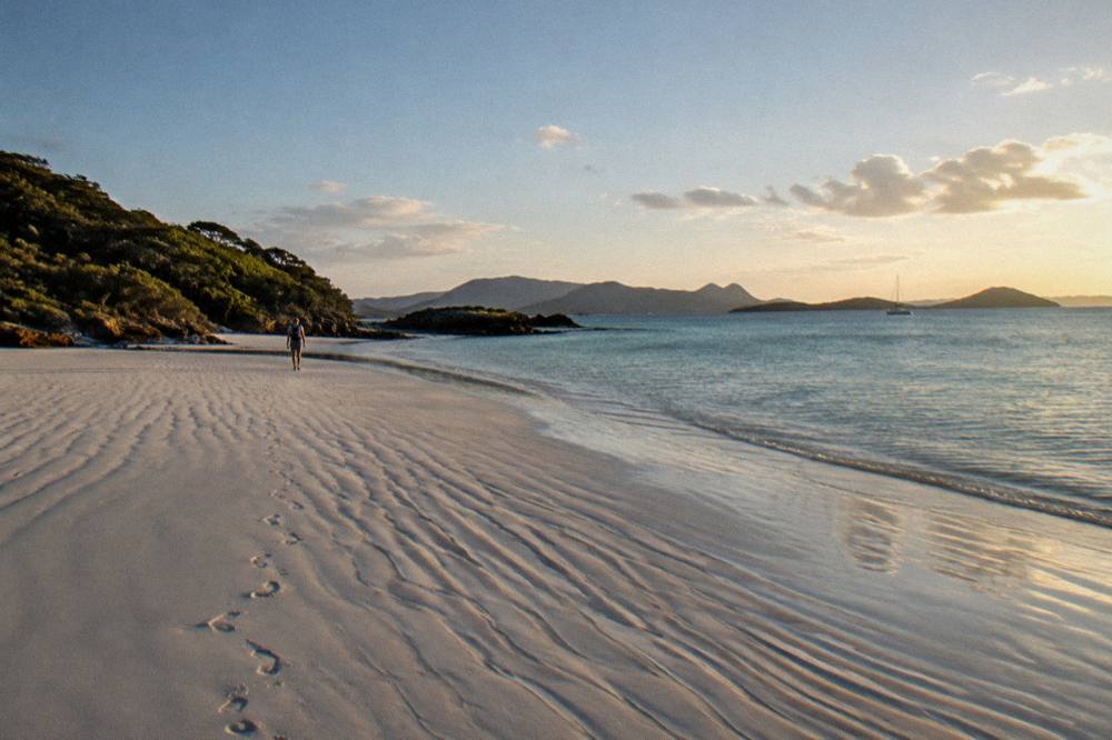 Whitehaven Beach at late afternoon with long shadows across white sand and calm clear water