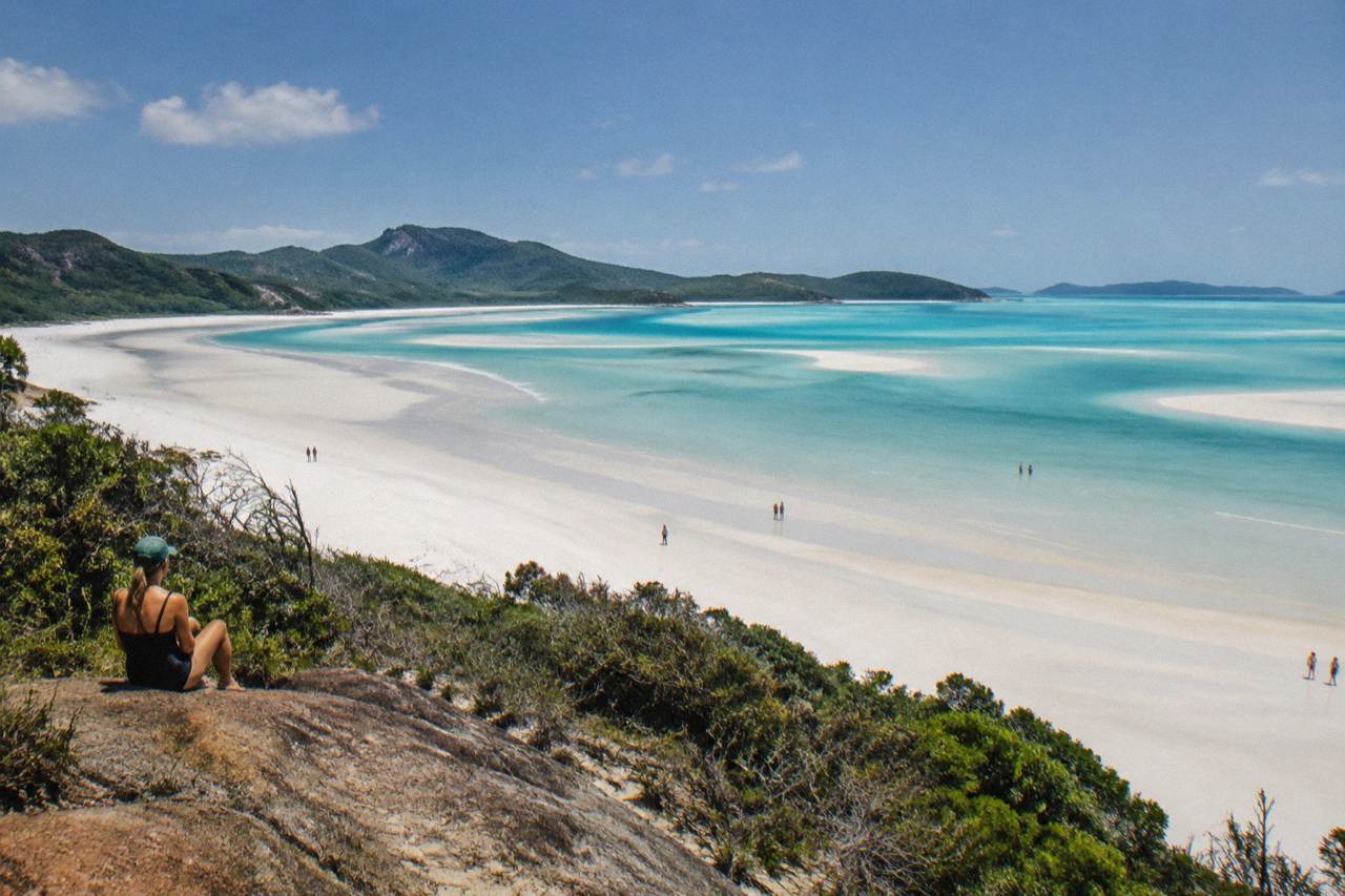 Whitehaven Beach curving into Hill Inlet with pale turquoise water and white silica sand under a clear sky