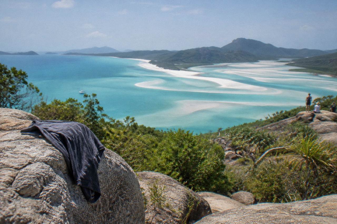 White silica sand shoreline and turquoise tidal inlet seen from a forested headland