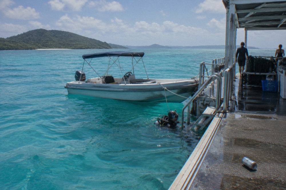 A pontoon moored over pale blue reef water with a small boat alongside