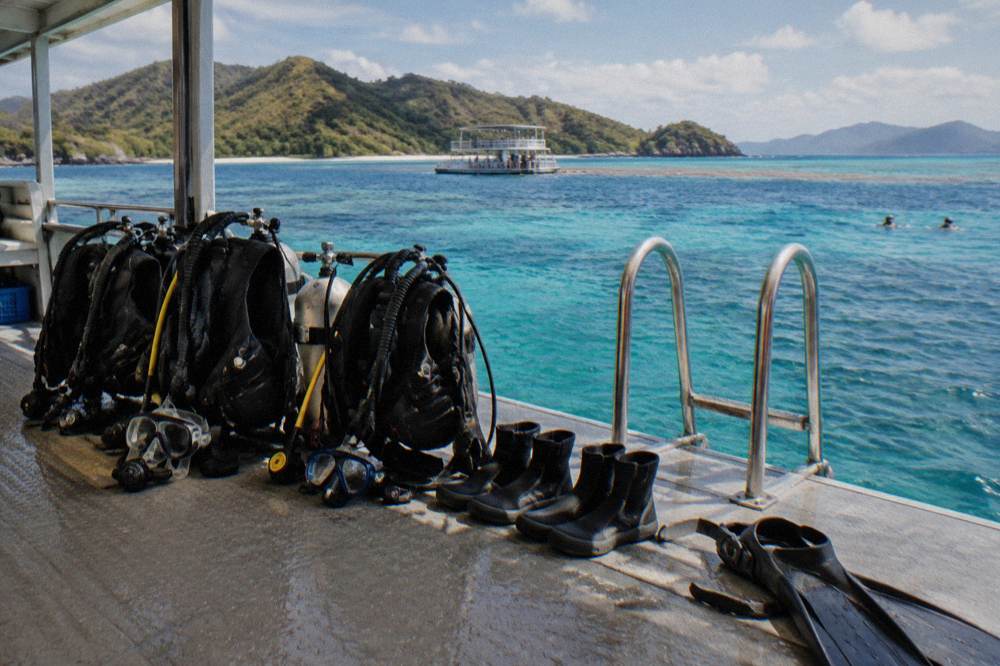 Scuba equipment arranged on a pontoon deck beside a dive ladder