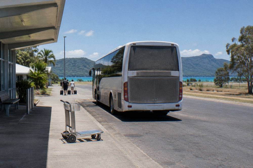 A regional coach parked at a small airport kerb under a blue sky