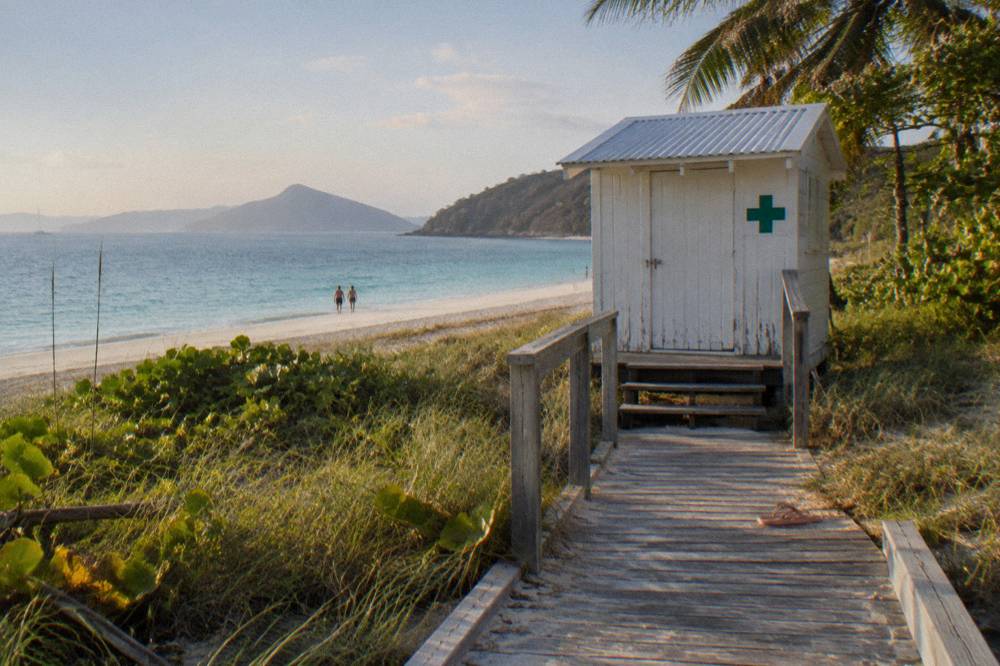 A white first aid station and emergency sign on a tropical beach boardwalk